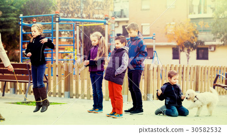 Children playing rubber band jumping game and laughing Children playing rubber band jumping game and laughing 30582532