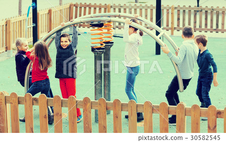 glad girl with long hair in school age sitting on swing on children's playground outdoors 30582545
