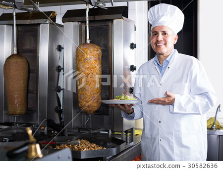 man chef wearing uniform cutting meat for kebab on kitchen in fast food restaurant man chef wearing uniform cutting meat for kebab on kitchen in fast food restaurant 30582636