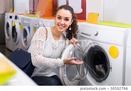 Woman choosing new laundry machine. 30582766