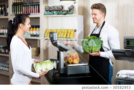 Man seller helping customer to weigh purchases 30582953