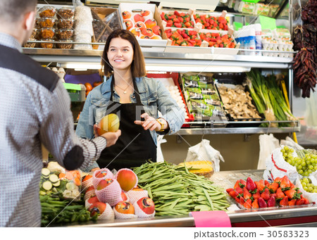 Smiling female seller assisting customer to buy fruit and vegetables in grocery shop Smiling female seller assisting customer to buy fruit and vegetables in grocery shop 30583323