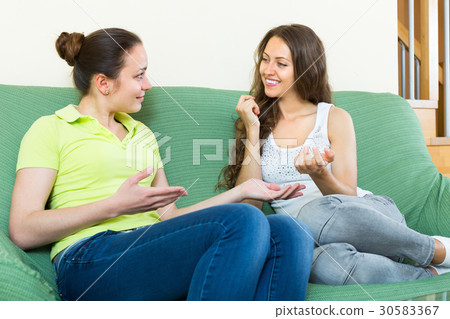 Two girls gossiping on sofa at home. Two girls gossiping on sofa at home. 30583367