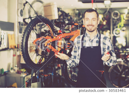 Man working on master mechanic assembling bicycle equipment 30583461