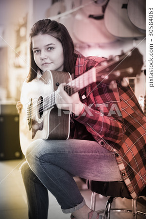 Young girl is deciding on acoustic guitar 30584063