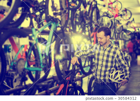 Man considers bicycle handlebar in store Man considers bicycle handlebar in store 30584312