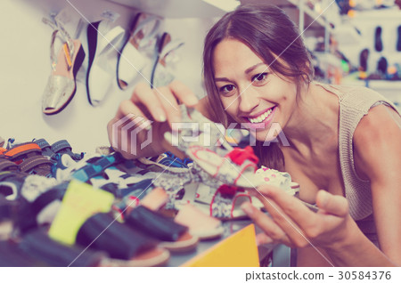 Portrait of woman looking after pair of shoes for kid Portrait of woman looking after pair of shoes for kid 30584376