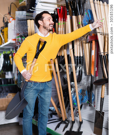 Man choosing new shovel in garden equipment shop Man choosing new shovel in garden equipment shop 30585196