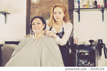 Woman is satisfied with work of young haircutter 30585228