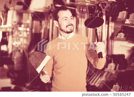 Man choosing various tools in garden equipment shop Man choosing various tools in garden equipment shop 30585247
