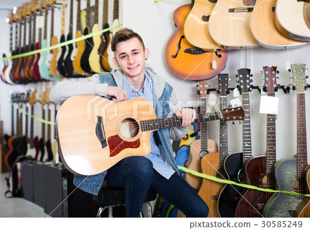 Boy is choosing quality acoustic guitar Boy is choosing quality acoustic guitar 30585249