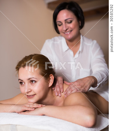 Masseuse massaging shoulders of woman 30585292