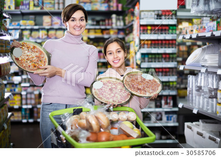 Young woman with daughter choosing pizza in supermarket 30585706