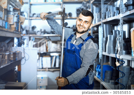 Positive male worker showing various tools Positive male worker showing various tools 30585853
