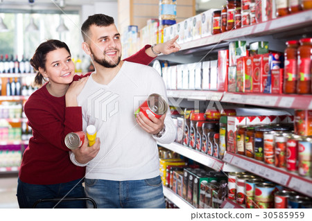 friendly couple choosing purchasing canned food for week at supermarket friendly couple choosing purchasing canned food for week at supermarket 30585959