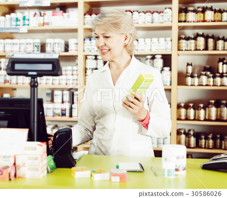 Smiling female seller checking assortment in store Smiling female seller checking assortment in store 30586026