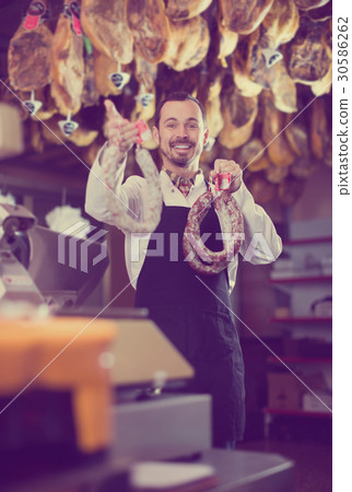 Smiling male seller showing sausages 30586262