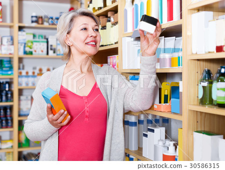 Attractive female client browsing rows of skin care products 30586315