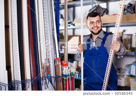 Young man worker examining plastic corners for tiles and floors 30586345