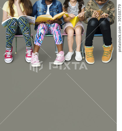 Diverse group of kids sitting in a row reading books 30588779