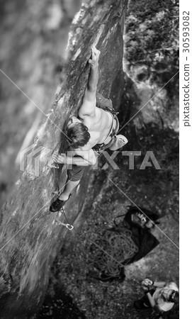 Rock climber climbs on cliff wall with rope 30593082
