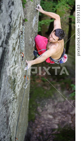 Rock climber climbs on cliff wall with rope 30593183