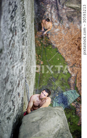 Rock climber climbs on cliff wall with rope 30593213