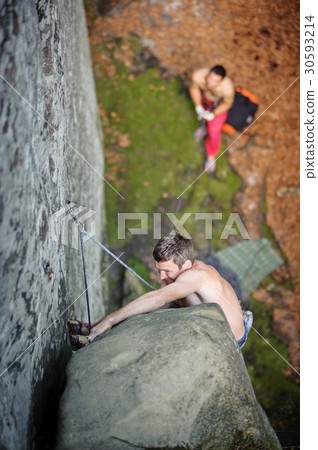 Rock climber climbs on cliff wall with rope 30593214