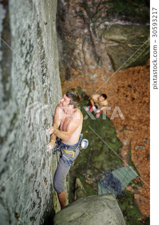 Rock climber climbs on cliff wall with rope 30593217