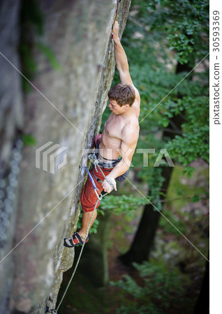 Muscular rock climber climbs on overhanging cliff 30593369