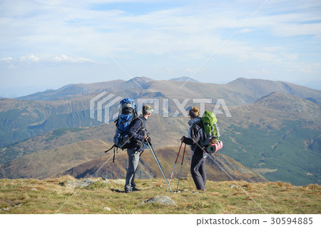 Couple hikers in the mountains with backpacks Couple hikers in the mountains with backpacks 30594885