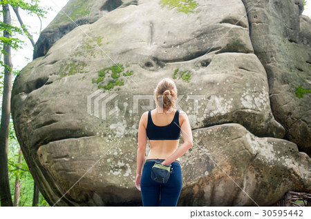 Woman with climbing equipment in front of a stone Woman with climbing equipment in front of a stone 30595442