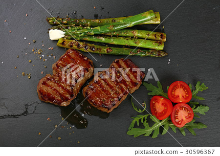 Two grilled beefsteak on black slate board Two grilled beefsteak on black slate board 30596367