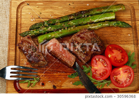 Cut slices of grilled beefsteak on board close up 30596368