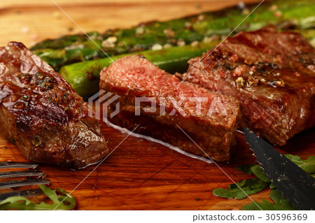 Cut slices of grilled beefsteak on board close up Cut slices of grilled beefsteak on board close up 30596369