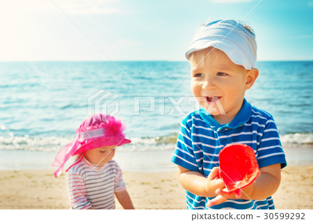 Babygirl and babyboy playing on the beach Babygirl and babyboy playing on the beach 30599292