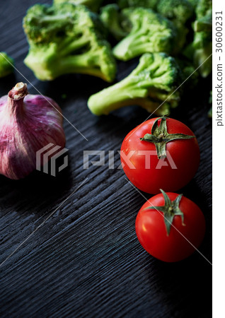 Broccoli, tomatoes and garlic lying on a dark Broccoli, tomatoes and garlic lying on a dark 30600231