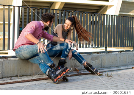 Couple on rollerblades is sitting. 30601684