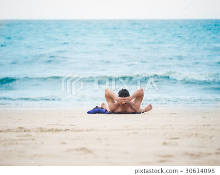 Man laying on the beach enjoying summer 30614098