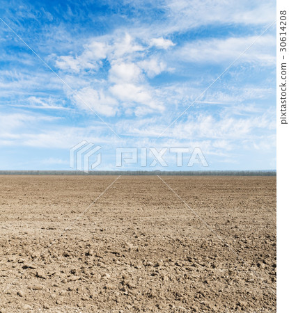 black plowed field and blue sky with clouds 30614208