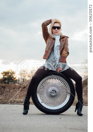 Sexy young girl sits on a large wheel Sexy young girl sits on a large wheel 30620872