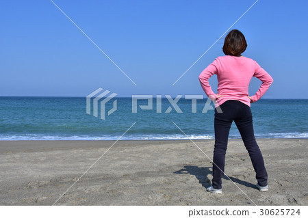 A woman standing on the beach 30625724