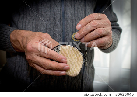 An elderly man in a hand holds a coin and a wallet An elderly man in a hand holds a coin and a wallet 30626040