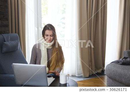Woman on armchair with computer and cell phone Woman on armchair with computer and cell phone 30626171