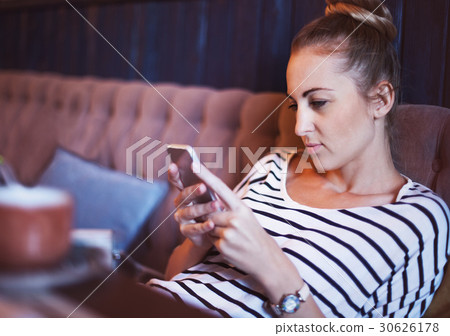 Beautiful girl using her mobile phone in cafe 30626178