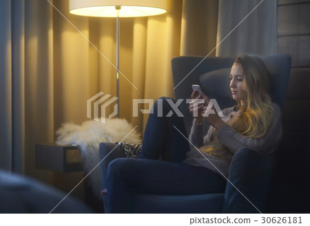 Woman lying on armchair using phone Woman lying on armchair using phone 30626181
