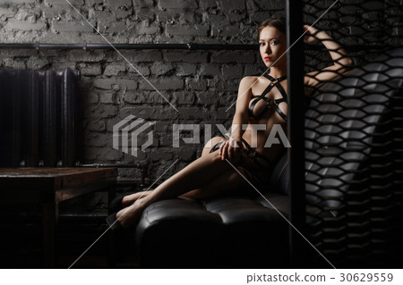 Sexy woman in black leather belts relaxing on sofa Sexy woman in black leather belts relaxing on sofa 30629559