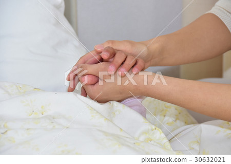 Parent holding child's hand in hospital bed 30632021