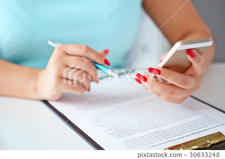 Woman working with mobile phone and holding a pen 30633248