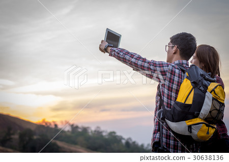 Tourists look at a map on the tablet on mountain. Tourists look at a map on the tablet on mountain. 30638136